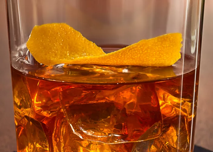 Glass of Old '97 garnished with orange peel on coaster