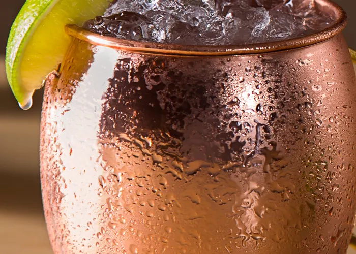 a copper mug of Moscow Mule garnished with ice and lime wedge