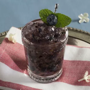 Glass of Blue Stallion Julep garnished with blueberry and mint leaves 
