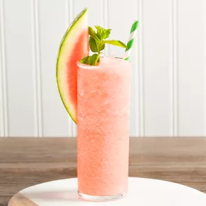 Glass of Downward Facing Daiquiri garnished with watermelon slice, mint leaves and a straws