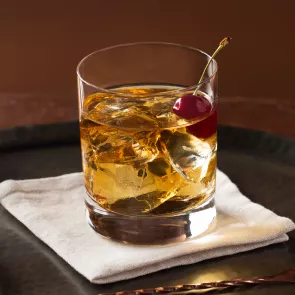 Glass of Buttershots® Old Fashioned garnished with cherry on white cloth