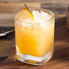 Glass of Bourbon Cider Sour garnished with a slice of apple and some crushed ice