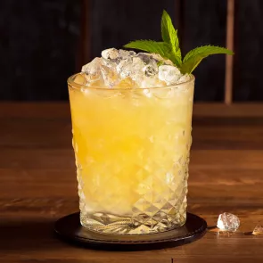  A Glass of Double Oak Whiskey Smash on coaster with crushed ice and garnished with mint leaves