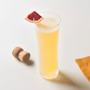 Glass of EFFEN® Blood Orange Mimosa garnished with blood orange wedge alongside cork bottle cap