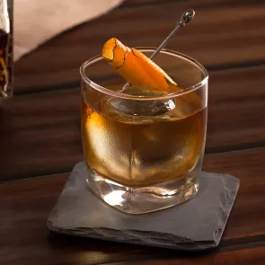 Glass of Rye Opener garnished with orange peel on coaster