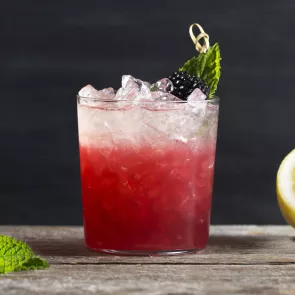 Glass of Independence Spice garnished with skewered mint leaf and blackberry