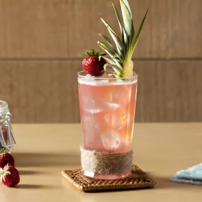 Glass of Bay Breeze garnished with pineapple leaves and strawberry