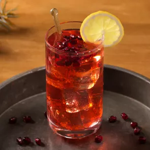 A glass of holiday wreath drink garnished with a lemon wedge on the rim.