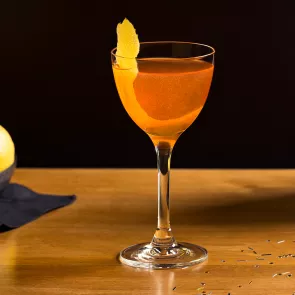 Glass of Kiss Me Cocktail garnished with lemon peel