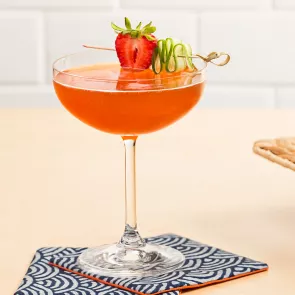 Glass of Melon Berry Mist garnished with strawberry and cucumber wheel on coaster