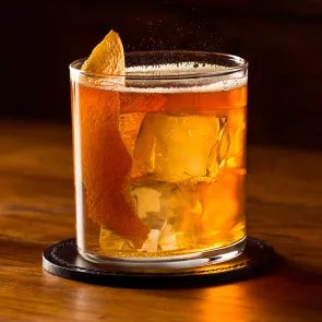 Flass of Rye Squeeze garnished with orange peel on coaster