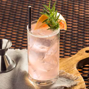 Glass of Paloma garnished with grapefruit wedge, rosemary sprig and straw