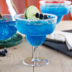 A glass of  Blue Margarita garnished with Lime, Blueberries and Salt 