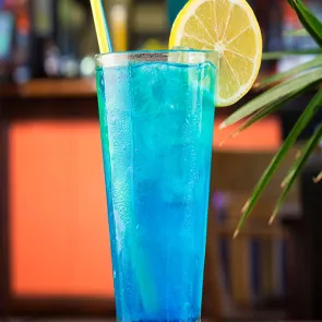 Glass of Sideline Sipper with ice cubes and straws garnished with lemon slice