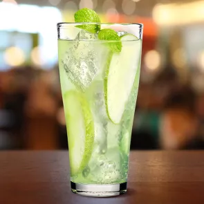 Glass of Sour Apple Highball with ice cubes and apple slices garnished with mint leaves