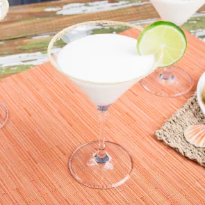 A glass of Key Lime Pie Martini garnished with wheel of lime on rim