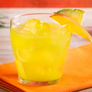 Glass of Pina Punch with ice, garnished with a mango and pineapple slice on an orange napkin. 