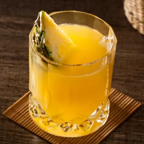 A glass of Pequeña Colada, garnished with a slice of pineapple  placed on a small piece of cardboad