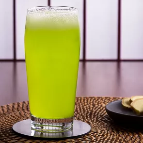 a glass of Midori and ginger beer liquid on a table