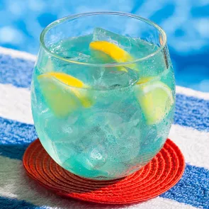 Glass of Pool Party Punch with ice and lemon slices on red coaster