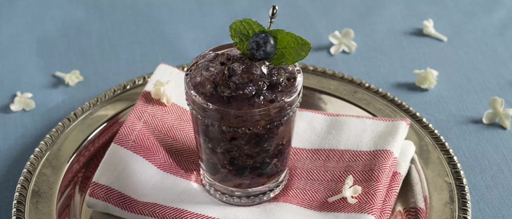 Glass of Blue Stallion Julep garnished with blueberry and mint leaves 