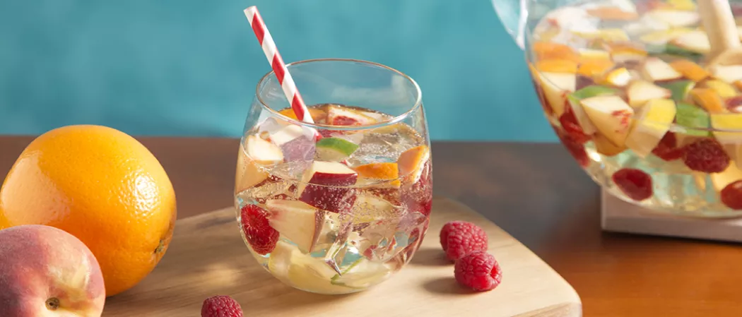 A glass with peach sangria filled with slices of fruits