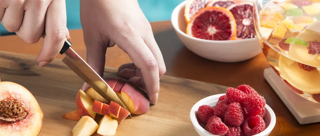 . A person skillfully slicing fruit on a wooden cutting board