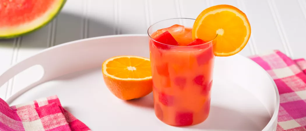 Glass of Juicy Screw garnished with orange slice alongside half orange