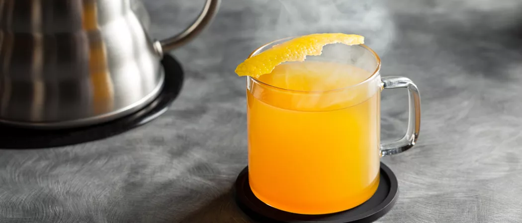 Cup of Jim Beam® Black Hot Toddy garnished with lemon peel on coaster