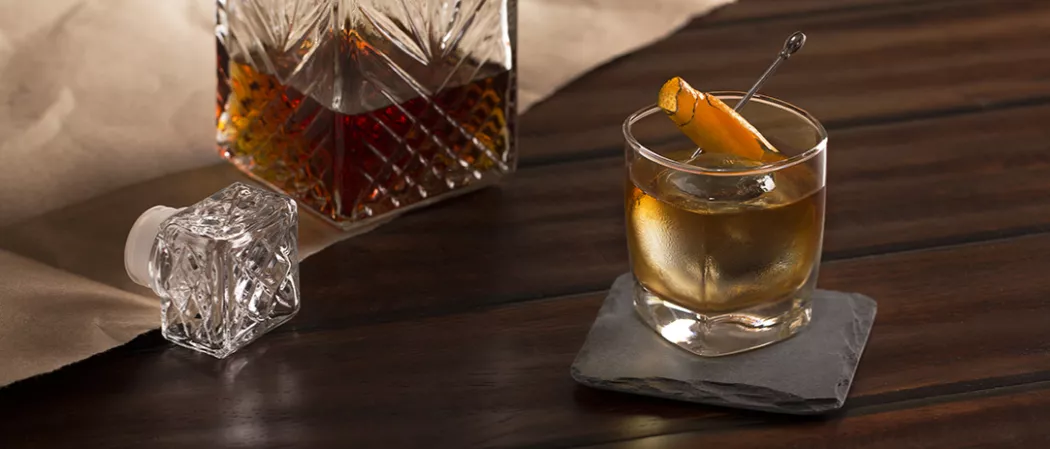 Glass of Rye Opener garnished with orange peel on coaster 