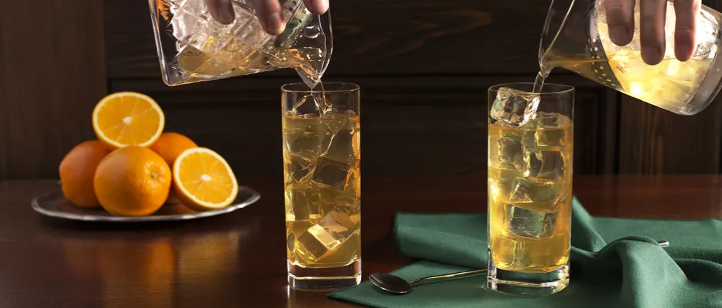Person pouring Derby Fizz into two glasses 