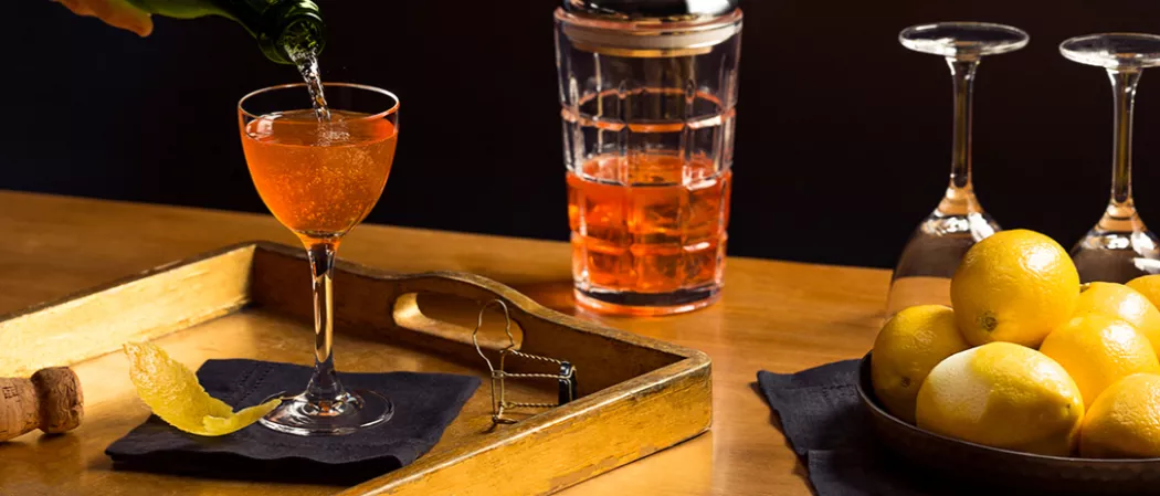 A tray with a glass of wine, a lemon, and a bowl of lemons, perfect for a refreshing drink or garnish.