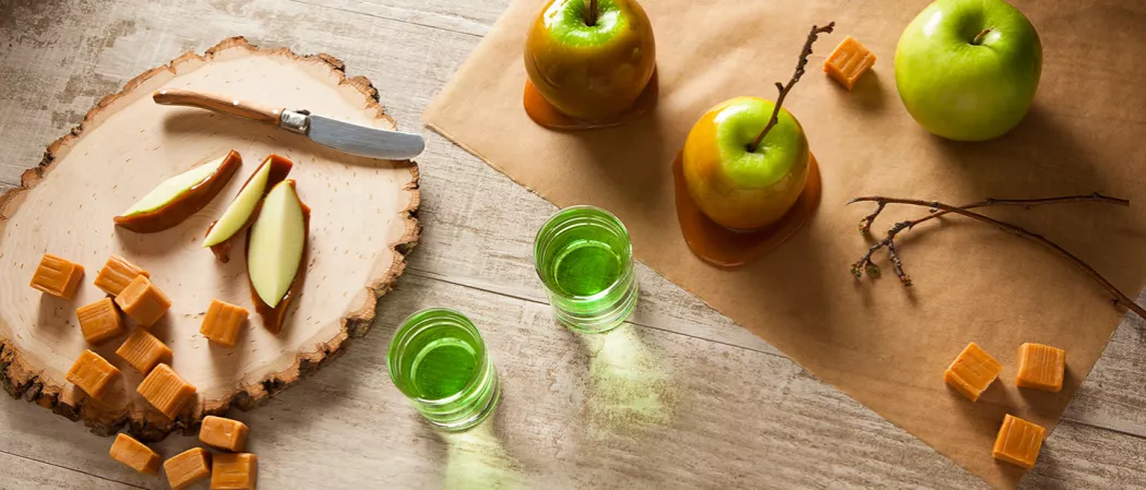 One glass with apple pices and caramel apple shot