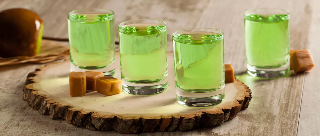 Four glass filled with caramel apple shot