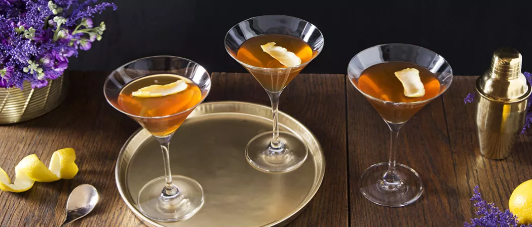 Three glasses of Courvoisier® Sidecar on bronze plate alongside a shaker
