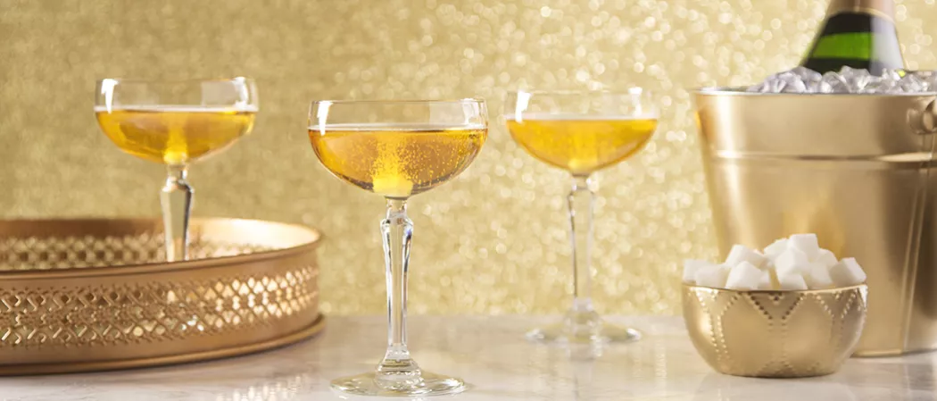 A person Pouring Sparkling Cognac into glass alongside bowl of pineapple wedges