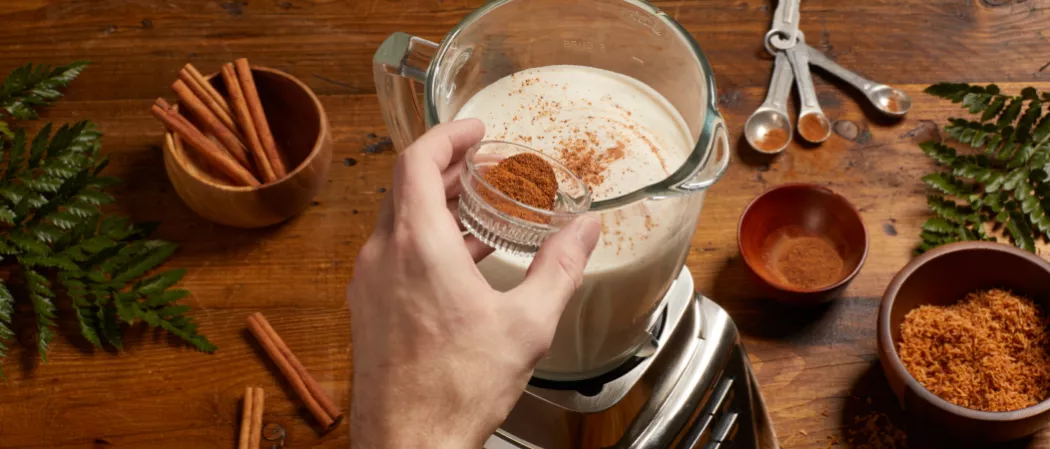 A person putting shredded cococnut in Sweetened Condensed Milk along with a bowl of cinnamon sticks  and shredded coconuts