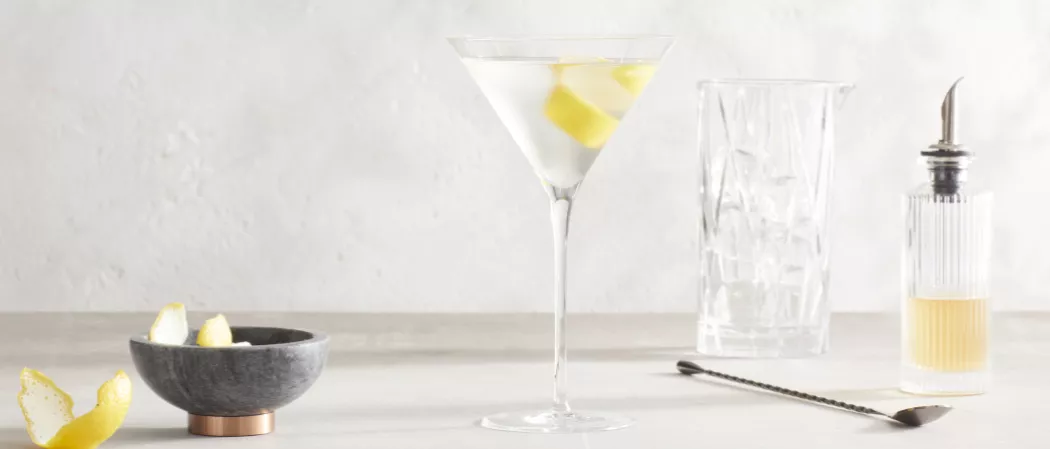 A glass of Haku® Martini garnished with Lemon Peel along with a bowl of lemon peel