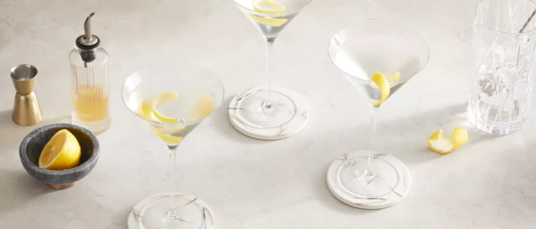 Three glasses of Haku® Martini garnished with Lemon Peel along with a bowl of chopped lemon