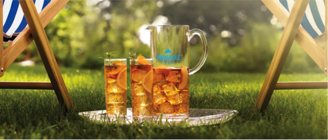 Two glasses of LemonWedge garnished with LemonWedge and leaves and Half & Half Punch in a jar