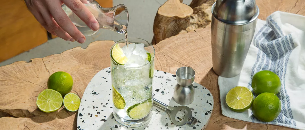 A person pouring Splash of Fresh Squeezed Lime Juice into a glass of Hornitos® Ranch Water along with chopped lemons 