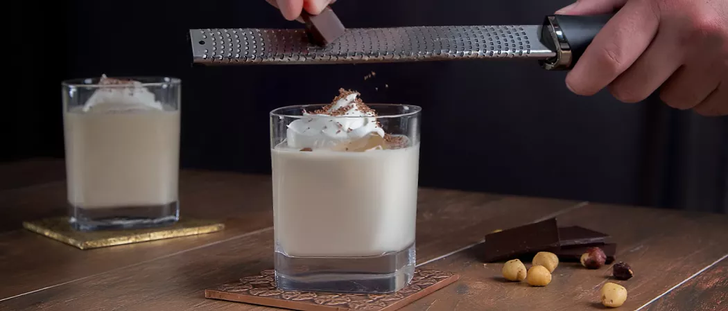 A person sliceing chocolate into a glass of bourbon ball