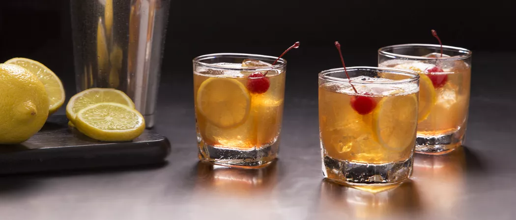 three glasses of Amaretto Sour garnished with lemon slice and a cherry