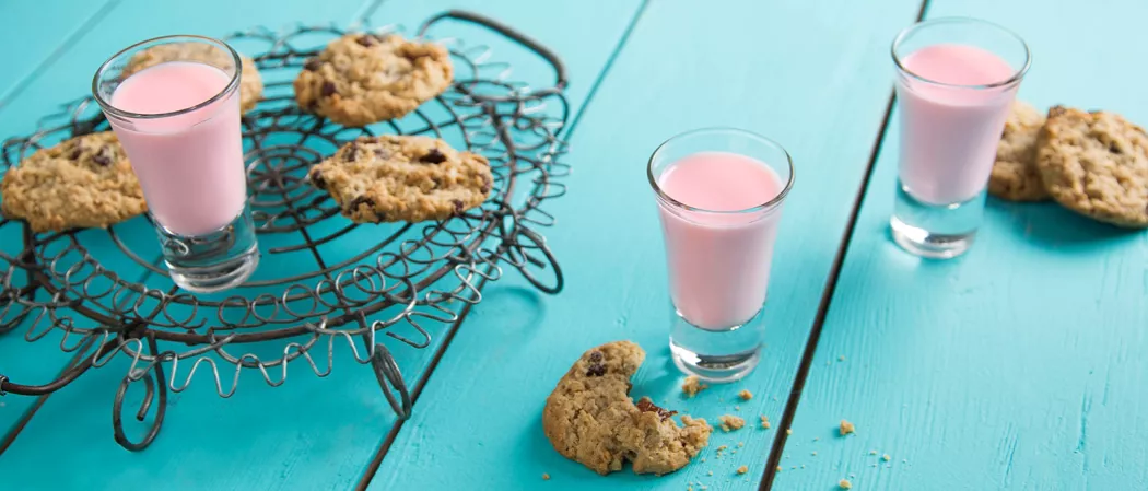 Two glasses of Oatmeal Cookie, accompanied by a few cookies on a black tray, alongside one glass of Oatmeal Cookie, half a piece of cookie, and two cookies