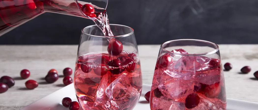 A person pouring Flirty Fizz in a glass alongside another glass of Flirty Fizz