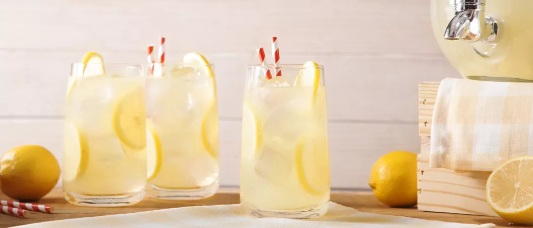 Three glasses of Vodka Lemonade garnished with lemon slices and straws