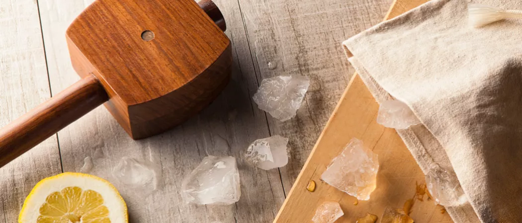 Ice smasher alongside some crushed ice and a lemon slice