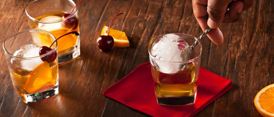 Three glass of old fashioned with ice and some pieces of orange