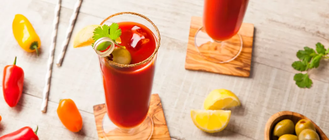One glass has blackberries and mint leaves, the other has the same with a wooden crusher.