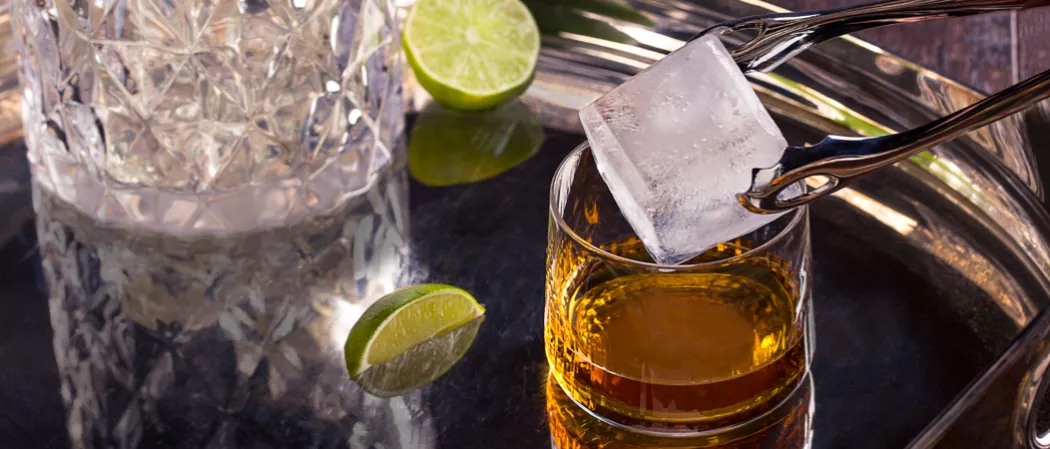 ice being put into glass of C.C.® & Ginger alongside lime slice